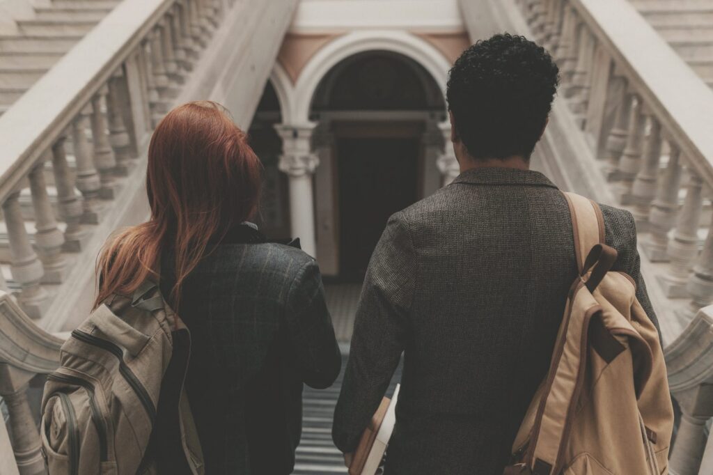 Two students seen from behind walking down a university staircase