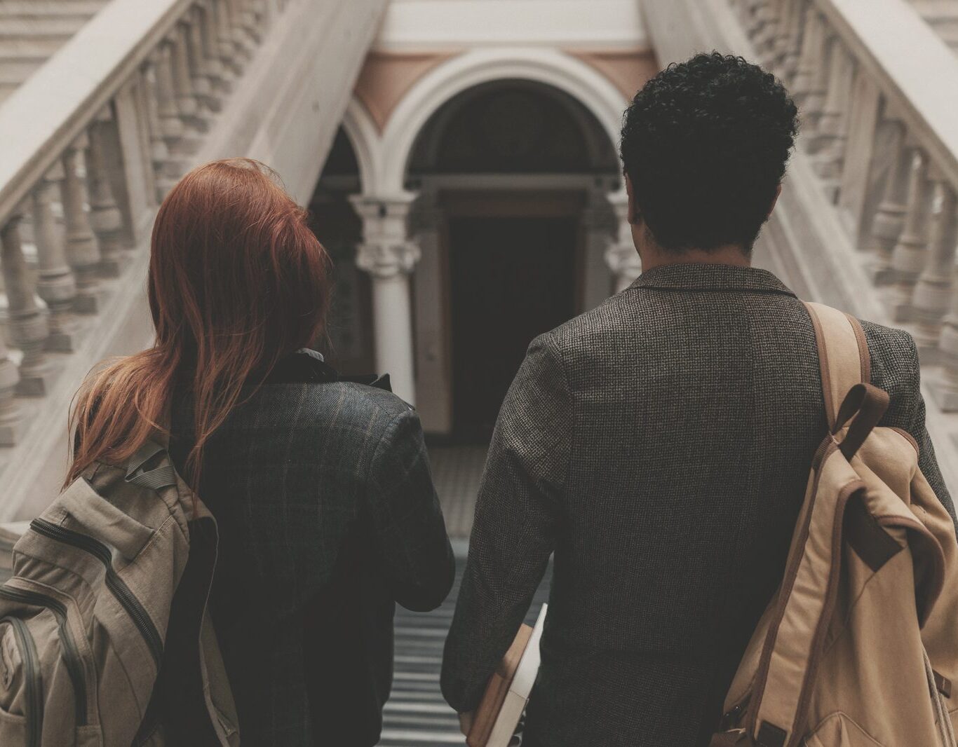 Two students seen from behind walking down a university staircase