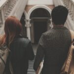 Two students seen from behind walking down a university staircase