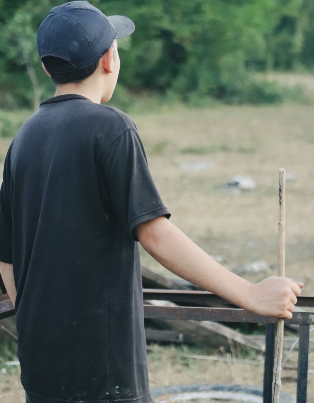 Teenage boy seen from behind, looking out over a field