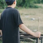 Teenage boy seen from behind, looking out over a field