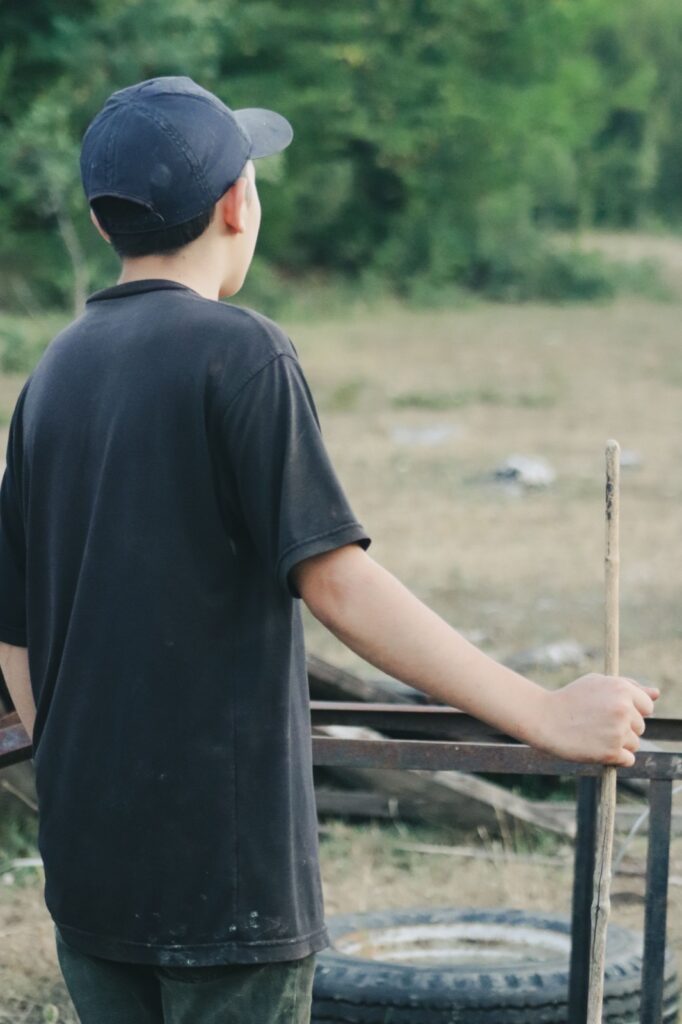 Teenage boy seen from behind, looking out over a field
